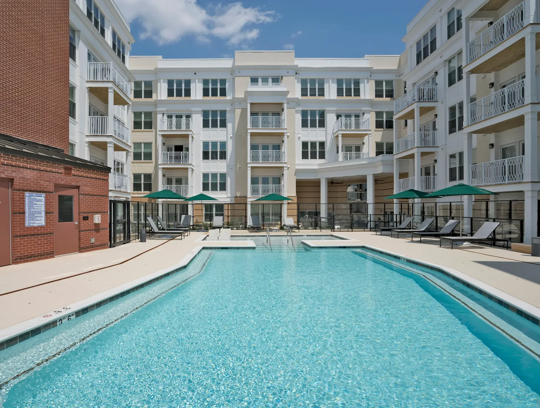 pool with deck seating surrounded by apartment balconies